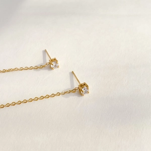 Macro detail of 18K gold chain earrings featuring sparkling clear round zircon stones