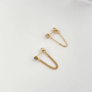 Detail of gold chain earrings with black zircon stone and asymmetrical U-shape design