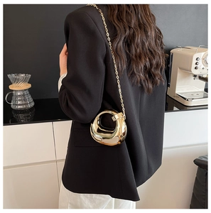 Detail of a minimalist gold geometric handbag with a sleek metallic mirror finish