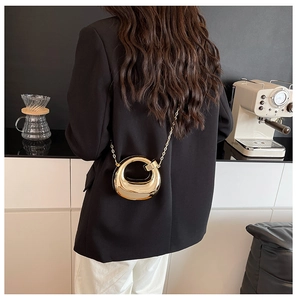 Close-up of golden mirrored acrylic crescent handbag with elegant metal chain strap