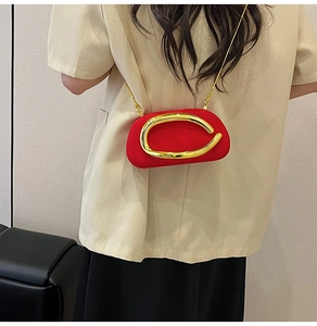 Rear view of a model wearing a red velvet mini bag with a large gold C-clasp and chain