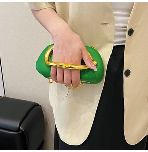 Detail of green cloud clutch bag with chunky gold metal handle and luxury leather texture