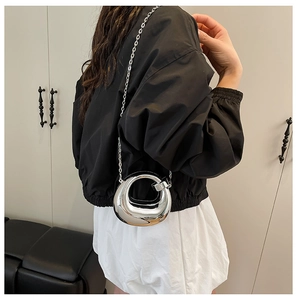 Detail of silver metallic ring bag with a sleek chain strap on a minimalist backdrop