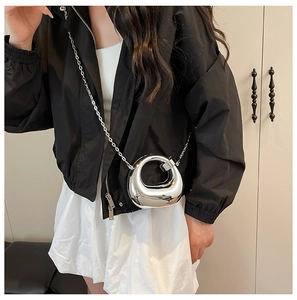 Detailed view of silver metallic circular crossbody bag with slim chain strap on model