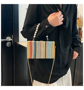 Detail of colorful woven crossbody bag with pearl handle and golden chain strap