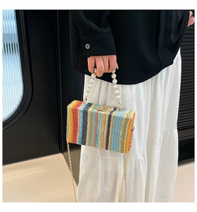 Macro detail of colorful woven texture and elegant pearl handle on a small straw crossbody bag