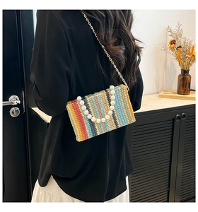 Detail of colorful striped straw woven bag featuring a pearl handle and gold chain strap
