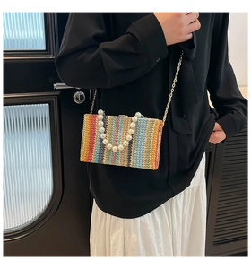 Close-up of colorful striped woven square bag with large pearl handle and gold chain strap