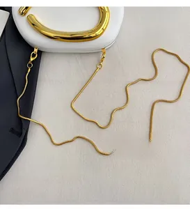 Detail of elegant gold snake chain strap and metallic handle on white hard clutch bag