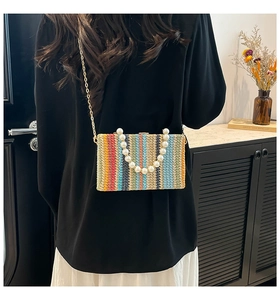 Detail of colorful woven straw bag featuring multi-color stripes and a large pearl handle