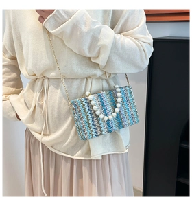 Detail of hand-woven crossbody bag featuring blue wave patterns and pearl handle strap