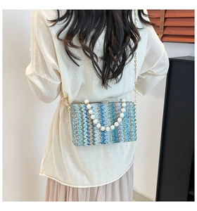 Detail of colorful woven straw bag featuring pearl handle and blue wavy pattern texture