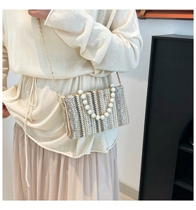 Detail of woven straw box bag with large pearl handle and chic metallic chain strap