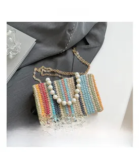 Detail of multi-color striped straw bag with luxury pearl handle and gold chain