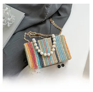 Detail of colorful woven shoulder bag with faux pearl handle and metal chain strap