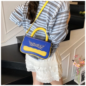 Model wearing a blue and yellow contrast box bag with silver thorn hardware