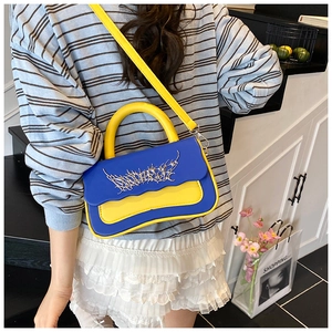 Detailed shot of trendy blue and yellow color-block crossbody bag with metal accent