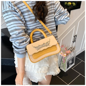 Detail of color-block box bag with flame metal buckle on a beige and yellow handbag