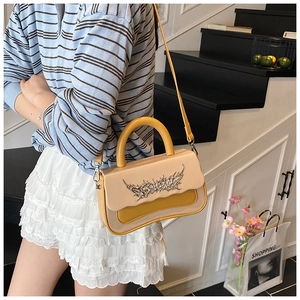 Detail of retro color-block handbag with gothic metal ornament and mustard yellow handle