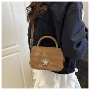 Detail of a brown woven texture shoulder bag with a sparkling star emblem and silver hardware