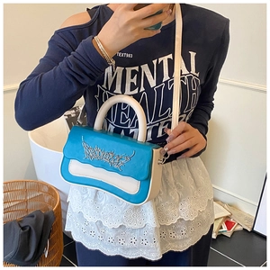 Close-up of stylish blue and white color-block handbag with metallic accent