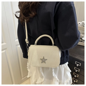 Close-up of white woven shoulder bag with rhinestone star detail on a model back view