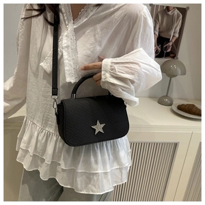 Chic black saddle bag with vertical stripe texture and sparkling star detail on a model