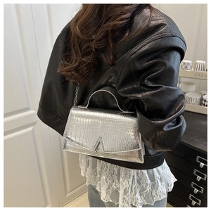 Detail of silver crocodile pattern crossbody bag with metal chain and A-shaped buckle