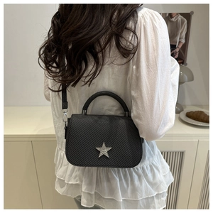 Detail of black crossbody bag with star-shaped crystal and fine diagonal texture