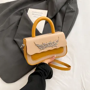 Detail of a chic two-tone crossbody box bag with wave flap and silver thorn hardware
