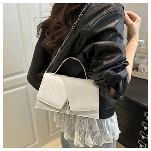 White faux leather crossbody bag with crocodile texture and silver chain strap on model
