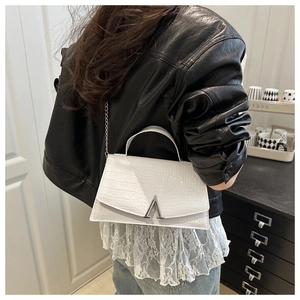 Detail of white crocodile pattern handbag with silver V buckle on a chain strap