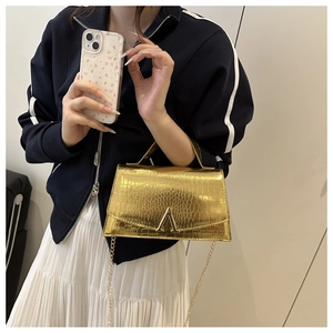 Detail of champagne gold crocodile texture and metallic buckle on women's handbag