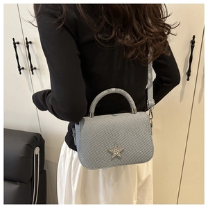 Detail der hellblauen strukturierten Handtasche mit silbernem Stern aus Strasssteinen
