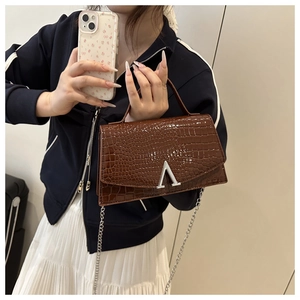 Close-up of dark brown crocodile pattern handbag with silver V-shaped buckle and chain