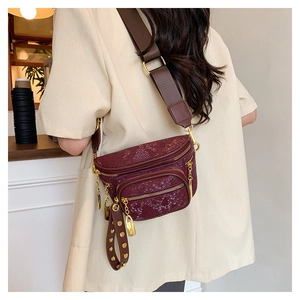 Detailansicht der bordeauxroten Tasche mit Schlangenmuster, Gold-Zippern und Kette