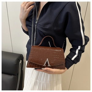 Brown crocodile pattern crossbody bag featuring silver A-logo buckle on a female model