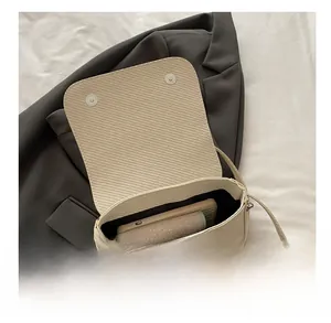 Detail showing the internal capacity of the off-white woven saddle bag with a phone