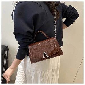 Detail of dark brown crocodile texture faux leather bag with silver metal A-shaped clasp