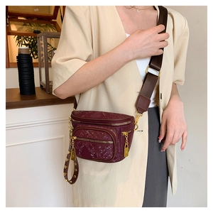 Details der burgunderroten Brusttasche mit Schlangenmuster und goldenen Reißverschlüssen