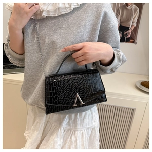 Detail of black faux crocodile leather bag with silver A-shaped magnetic buckle