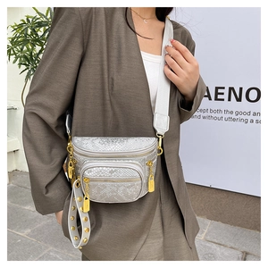 Nahaufnahme der silbernen Schlangenhaut-Brusttasche mit goldfarbenen Details und breitem Gurt