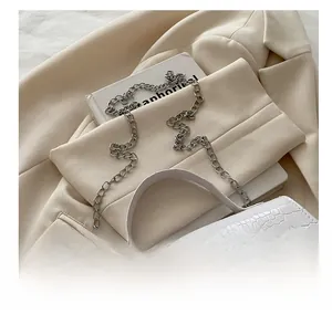 Close-up of a white croc-embossed handbag with elegant silver chain shoulder strap