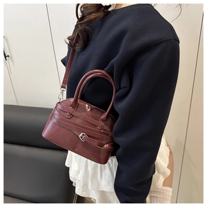 Détail du sac à main shell en cuir rouge foncé avec boucle porté par un modèle