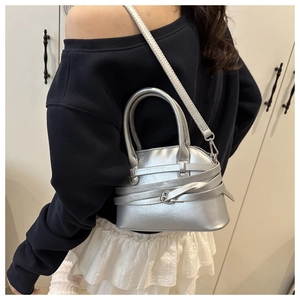 Detail of silver metallic PU leather handbag with decorative strap and round handles