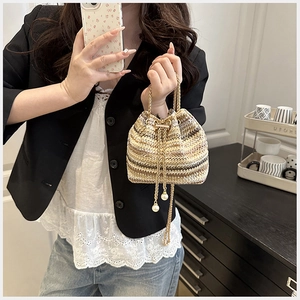 Détail du sac seau en paille tissée avec glands en perles et bandoulière chaîne dorée