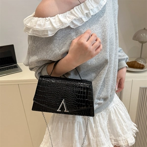 Chic black crocodile embossed crossbody bag with silver hardware on a lifestyle model