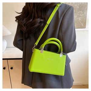 Neon green litchi texture crossbody bag worn over a grey blazer for a modern style