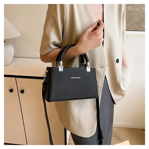Detail view of black litchi pattern leather handbag with silver hardware and fashion text
