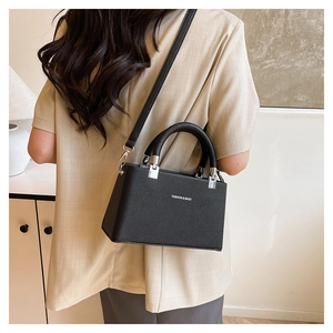 Rear view of model wearing black litchi pattern crossbody bag with silver hardware